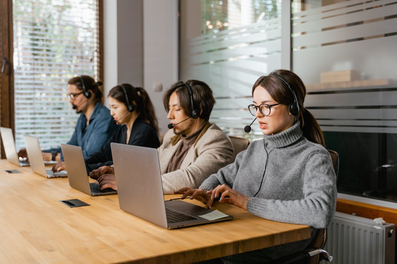 Call center team working at laptops with headsets, providing customer support.